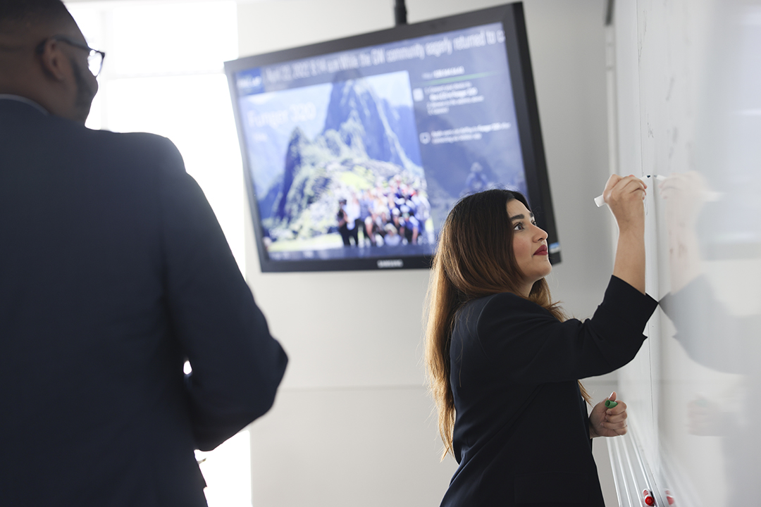 a GWSB MBA student writes on a dry-erase board during a consultancy project