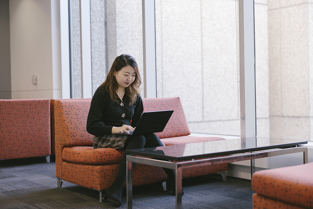 A GWSB MS in Business Analytics student studies on a couch in Duques Hall