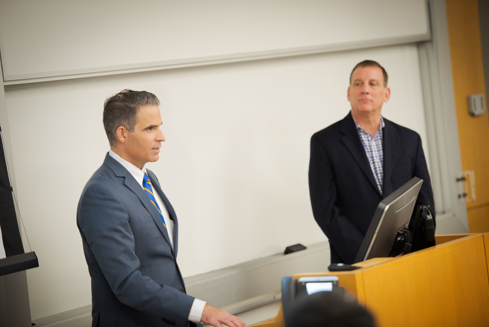Professor Rodney Lake speaks at a podium while an additional speaker stands to the side