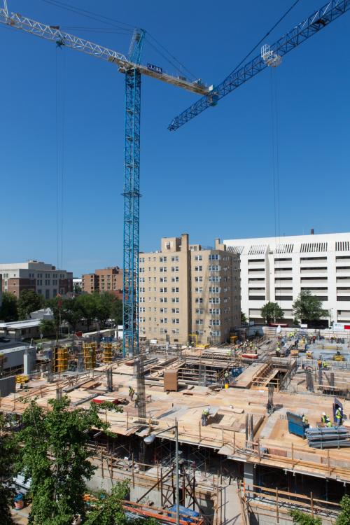 building under construction with two construction cranes