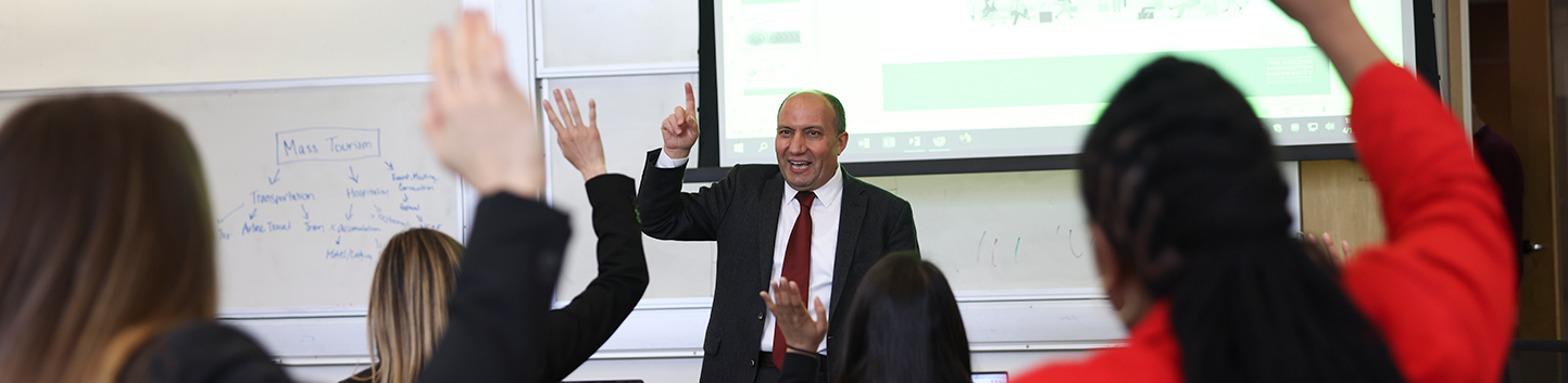 Professor Speaking in front of students raising their hands