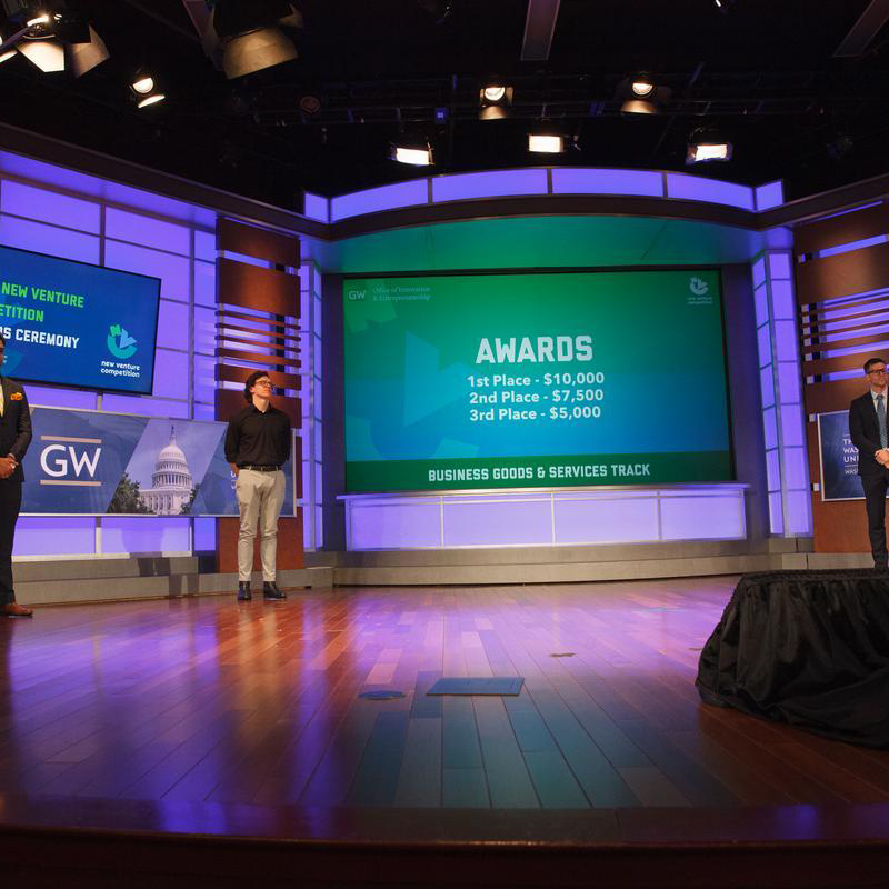 3 award winners standing on stage at new venture competition 
